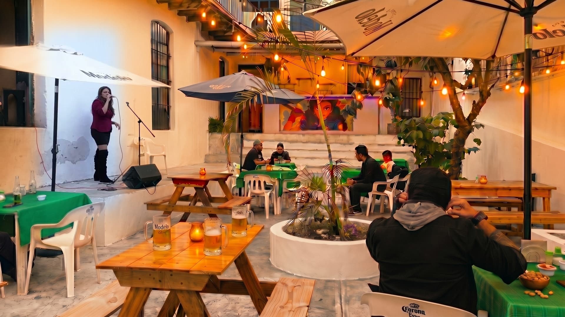 Elena Cuamba en vivo en La Macana — escenario bajo string lights, patio lleno al crepúsculo