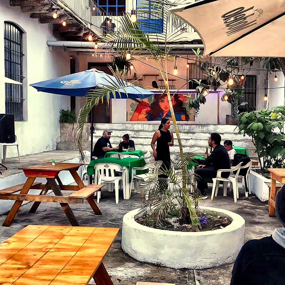 Patio al crepúsculo con grupos conversando bajo string lights