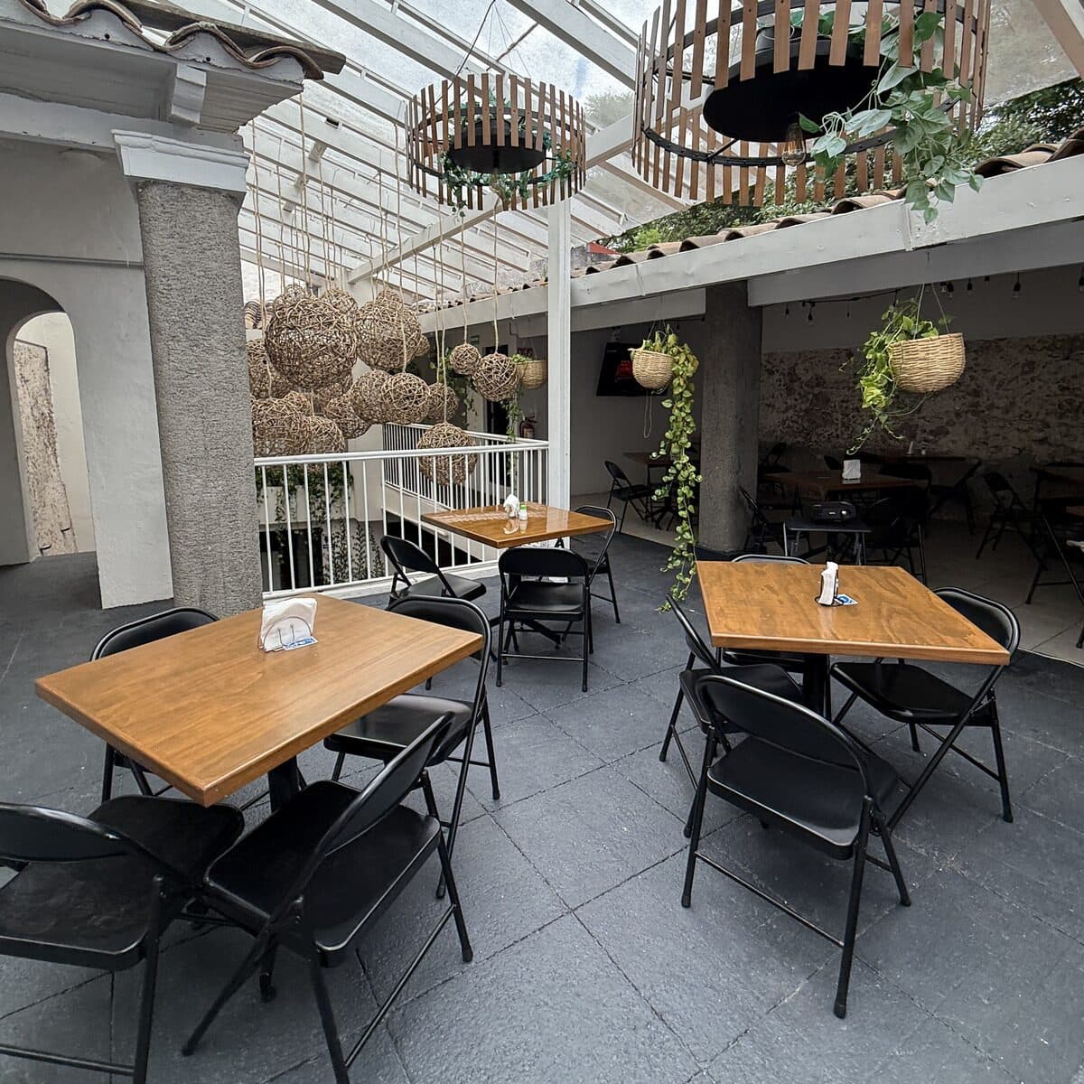 La terraza completa de día, con las mesas puestas y el piso de piedra